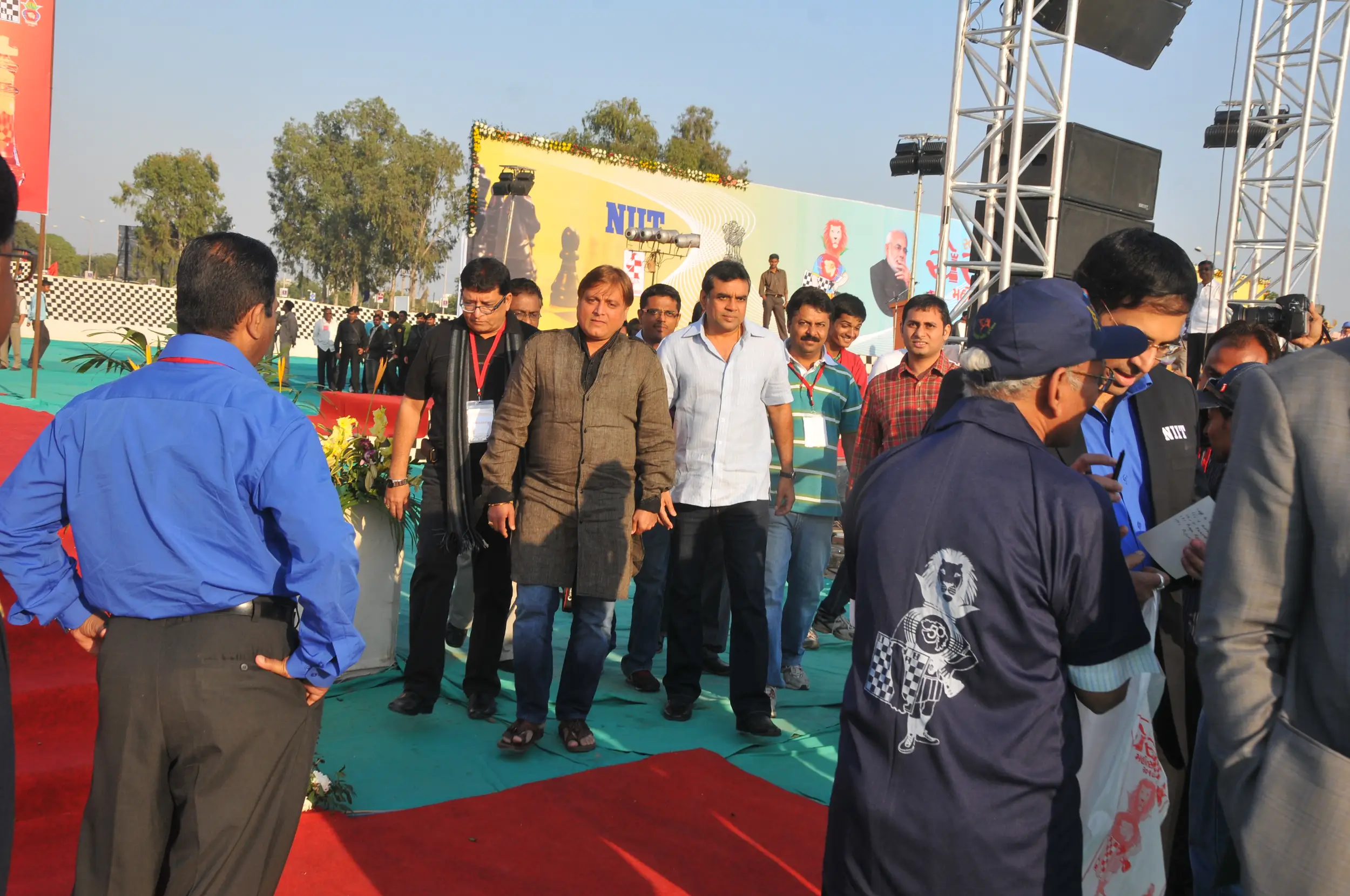 Men lighting ceremonial lamp at event with ITT banner in background