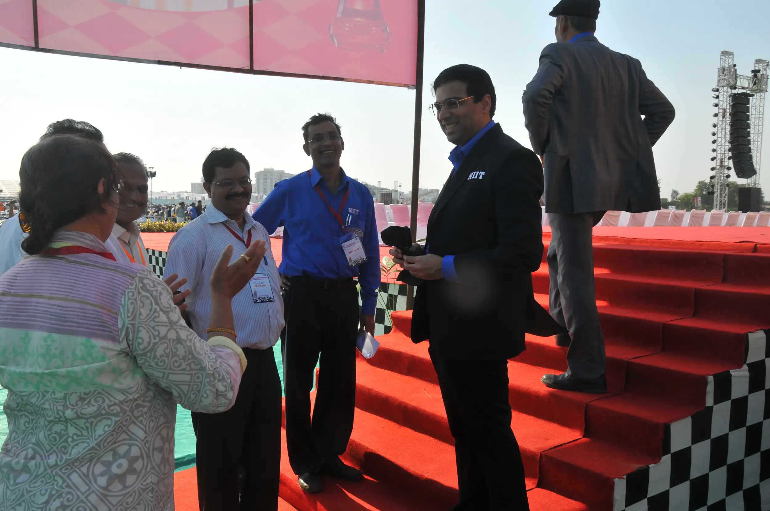 Men lighting ceremonial lamp at event with ITT banner in background